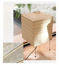 Akari 1X Table Lamp — lit shade standing on a stone floor by a window, fern in the background — Captains Bamboo