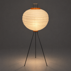 Akari 10D Floor Lamp — same shade lit, casting a warm pool of light onto the studio floor — Captains Bamboo