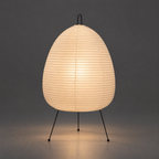 Akari 1A Table Lamp — lit warm glow through ribbed paper shade, light pooling below on grey backdrop — Captains Bamboo