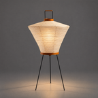 Akari 4A Table Lamp — lit flared shade glowing, warm light thrown onto the grey studio floor — Captains Bamboo