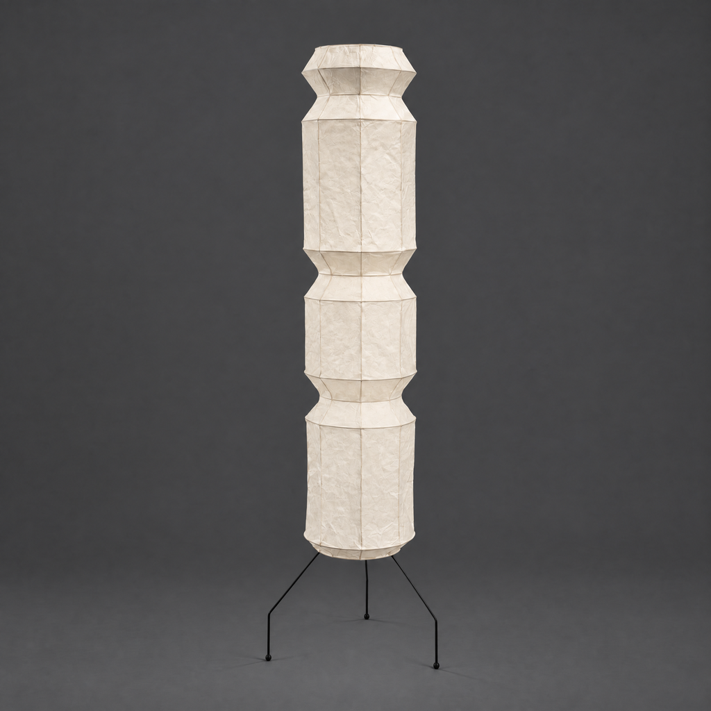 Akari UF4-L9 and UF4-L6 Floor Lamp — unlit faceted paper column on thin black tripod legs, grey studio wall — Captains Bamboo