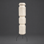 Akari UF4-L9 and UF4-L6 Floor Lamp — unlit faceted paper column on thin black tripod legs, grey studio wall — Captains Bamboo