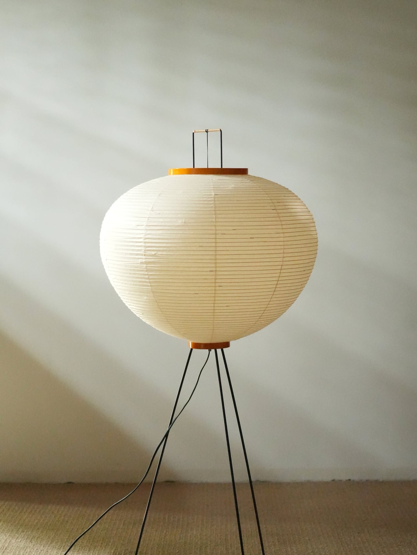 Akari 10A Floor Lamp — unlit shade standing on a tatami floor, daylight and window shadows behind — Captains Bamboo